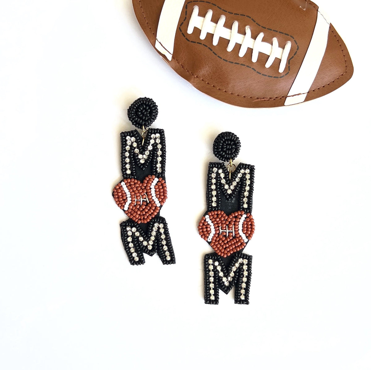 Hand-beaded Football Mom earrings with black and white MOM lettering and brown football centers